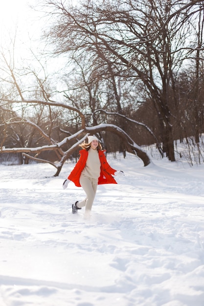 Una joven, rubia, con un suéter, un sombrero y una chaqueta naranja, en el contexto del paisaje invernal. Nieve y heladas, el concepto de Navidad.