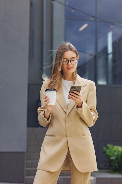 Una joven rubia con el telón de fondo de un centro de oficinas del centro de negocios Retrato de un traje informal de café inteligente de inicio exitoso