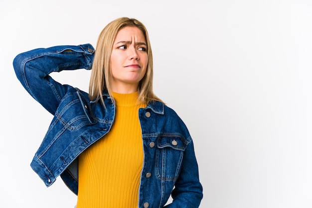 Joven rubia tocando la parte posterior de la cabeza, pensando y haciendo una elección