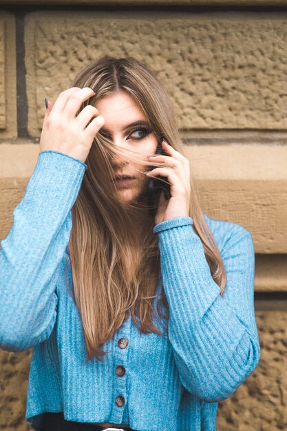 Joven rubia tomando por teléfono móvil en la calle