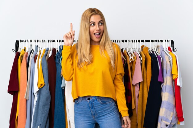 Foto joven rubia uruguaya en una tienda de ropa con la intención de darse cuenta de la solución mientras levanta un dedo