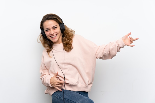 Joven rubia usando el móvil con auriculares y baile