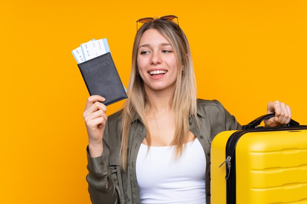 Joven rubia en vacaciones con maleta y pasaporte