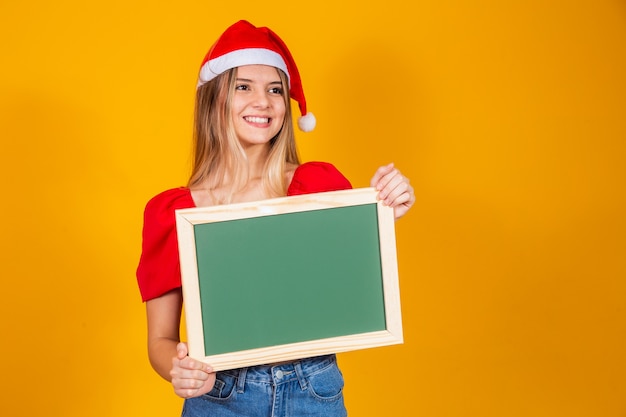 Joven rubia vestida para navidad sosteniendo un cartel. Navidad