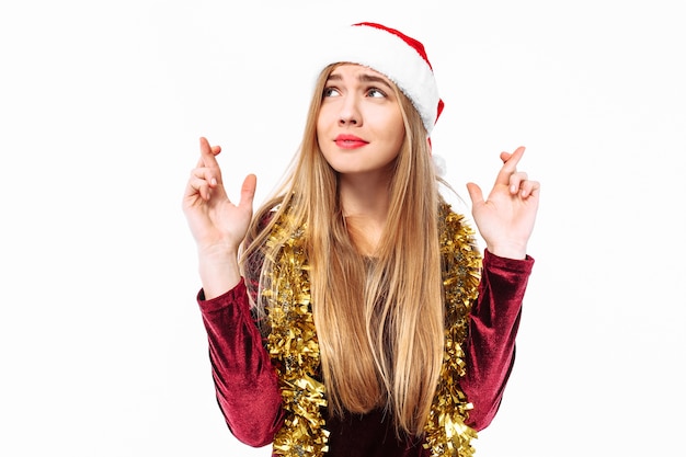 Joven rubia vistiendo un gorro de Papá Noel y oropel