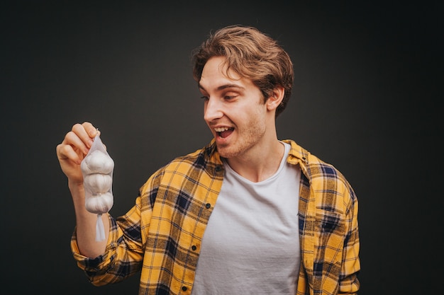 Foto joven rubio con camisa amarilla está sosteniendo ajos con sorpresa