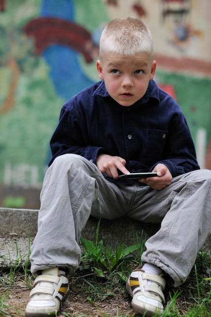 joven rubio jugando videojuegos al aire libre en el parque