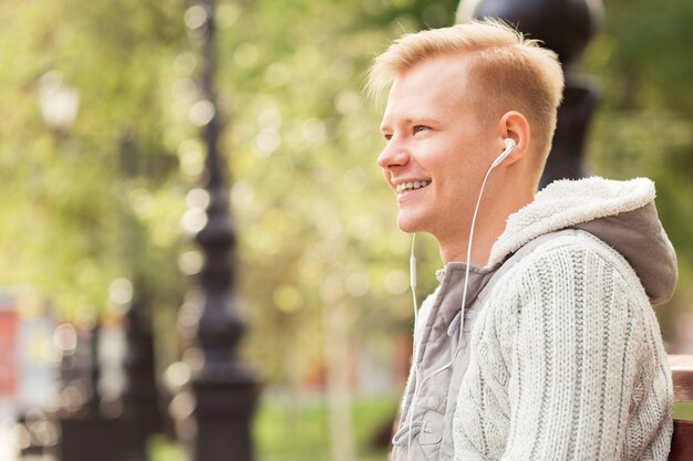 Joven rubio sentado y escuchando música con auriculares y tableta, concepto de estilo de vida