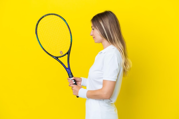 Joven rumana aislada de fondo amarillo jugando al tenis