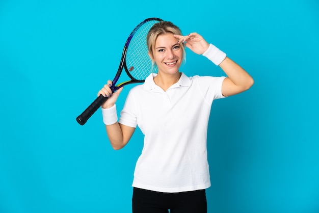 Joven rusa aislada en azul jugando al tenis