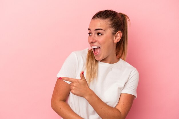 La joven rusa aislada sobre fondo rosa se ve a un lado sonriente, alegre y agradable.