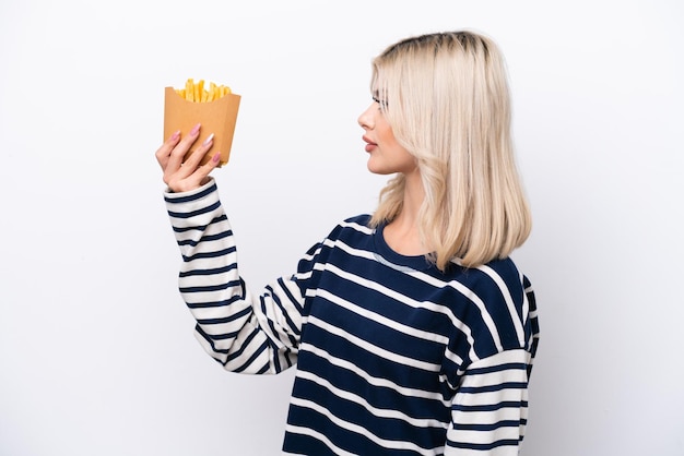 Joven rusa atrapando papas fritas aisladas de fondo blanco con expresión feliz