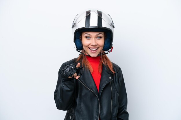 Joven rusa con un casco de motocicleta aislado de fondo blanco sorprendida y apuntando al frente