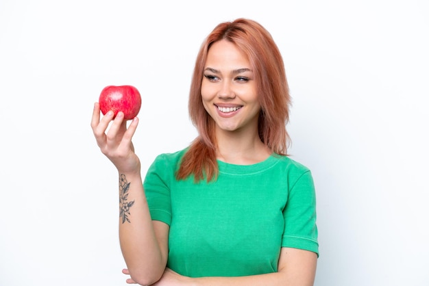 Joven rusa con una manzana aislada de fondo blanco con expresión feliz