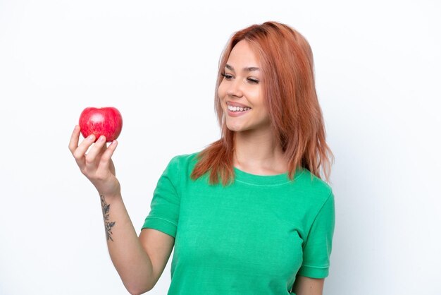 Joven rusa con una manzana aislada de fondo blanco con expresión feliz