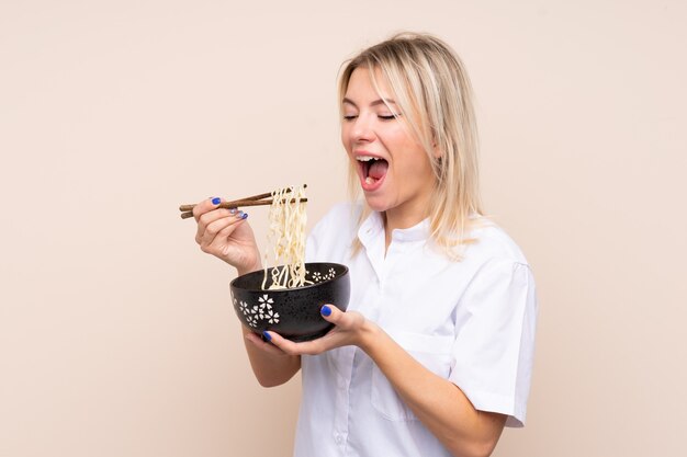 Joven rusa sosteniendo un plato de fideos con palillos y comiéndolo