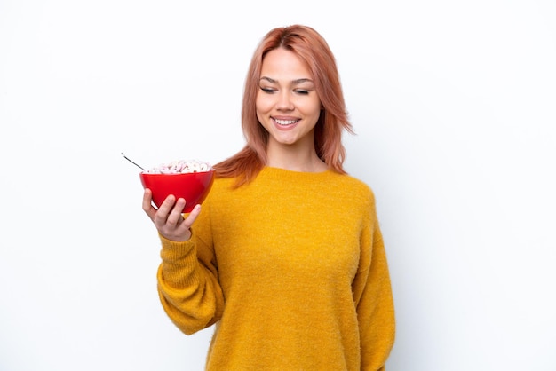 Joven rusa sosteniendo un tazón de cereales aislado de fondo blanco con expresión feliz