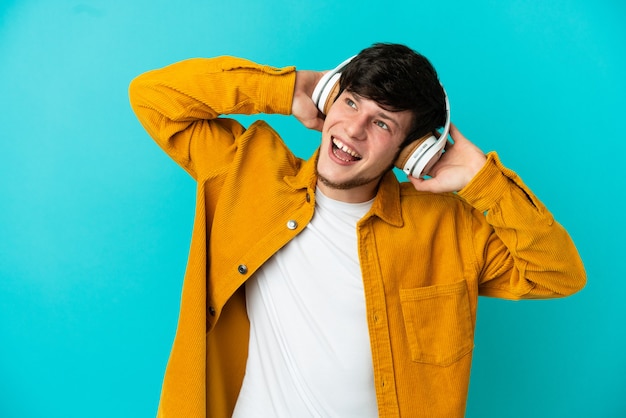 Foto joven ruso aislado sobre fondo azul escuchando música