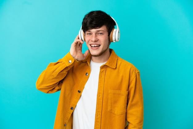 Joven ruso aislado sobre fondo azul escuchando música