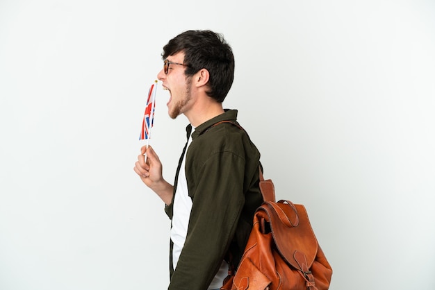 Foto joven ruso sosteniendo una bandera del reino unido aislado sobre fondo blanco riendo en posición lateral