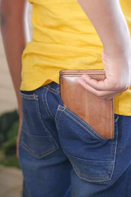 Foto joven sacando la billetera del bolsillo trasero