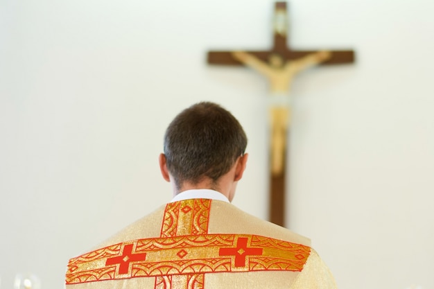 Joven sacerdote católico en ropa amarilla arcos