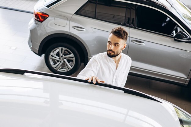 Joven en la sala de exposición de automóviles eligiendo un automóvil