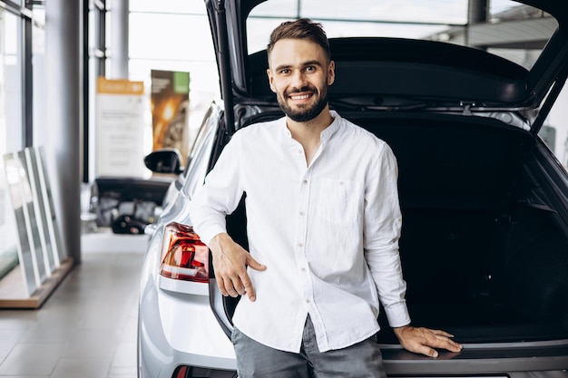 Joven en la sala de exposición de automóviles eligiendo un automóvil