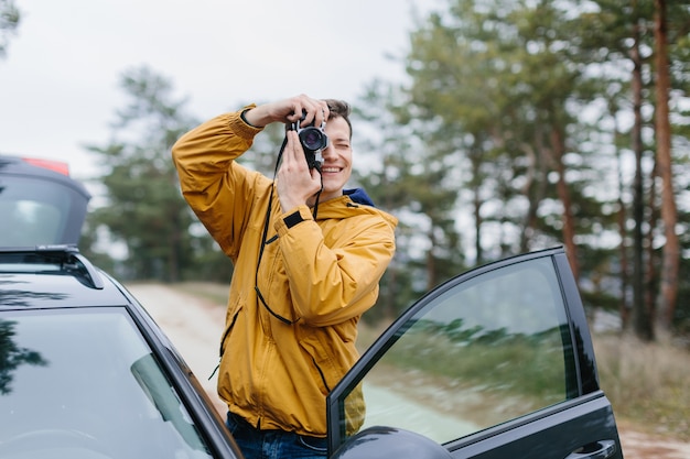 Joven salió de su automóvil para tomar una foto con una cámara de película en el bosque