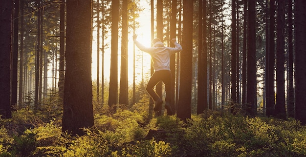 Joven saltando al bosque al atardecer