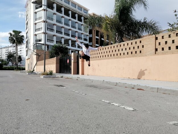 Foto joven saltando en la carretera contra el edificio