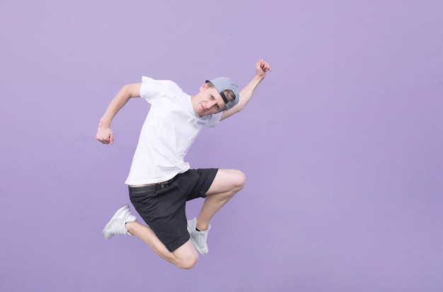 Joven saltando contra el fondo de una pared morada