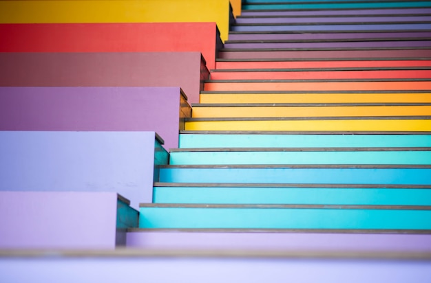 Joven saltando en la escalera arcoiris colorido