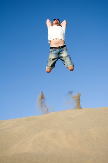 Joven saltando sobre una duna