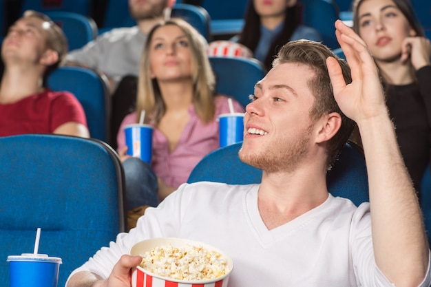 Joven saludando a alguien sonriendo alegremente en el cine