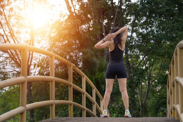 Una joven sana usa ropa deportiva haciendo estiramientos antes de hacer ejercicio al aire libre en el parque