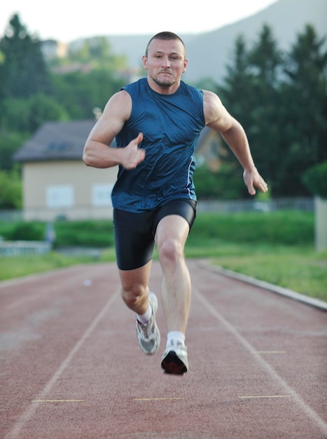 un joven sano corre en una pista deportiva de carreras atléticas y representa el concepto de tipo y velocidad