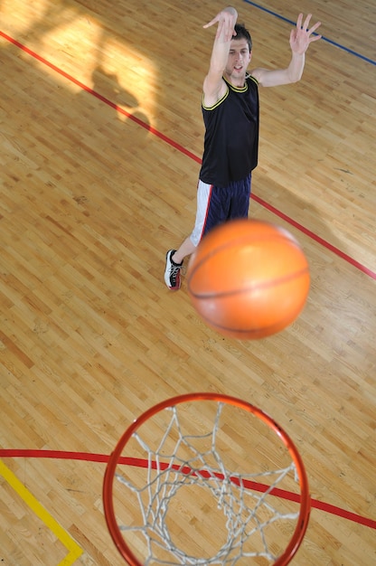 un joven sano juega al baloncesto en el gimnasio de la escuela interior