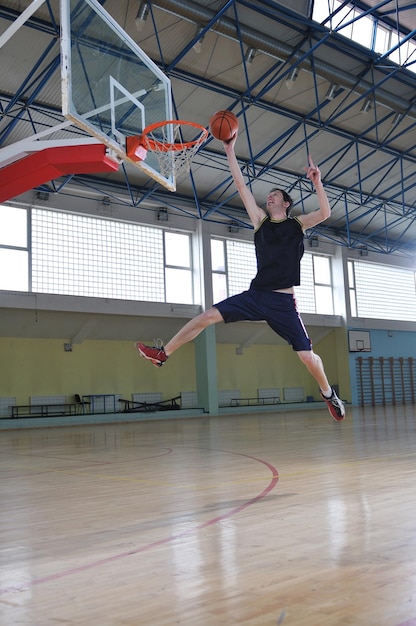 un joven sano juega al baloncesto en el gimnasio de la escuela interior