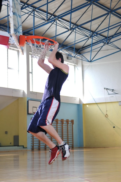 Un joven sano juega al baloncesto en el gimnasio de la escuela.