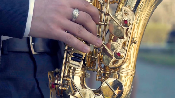 Foto joven con saxofón afuera cerca de la vieja pared pintada joven músico expresivo tocando el