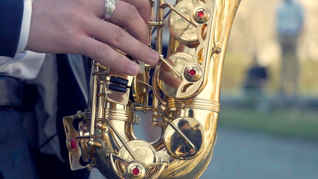 Joven con saxofón afuera cerca de la vieja pared pintada joven músico expresivo tocando el