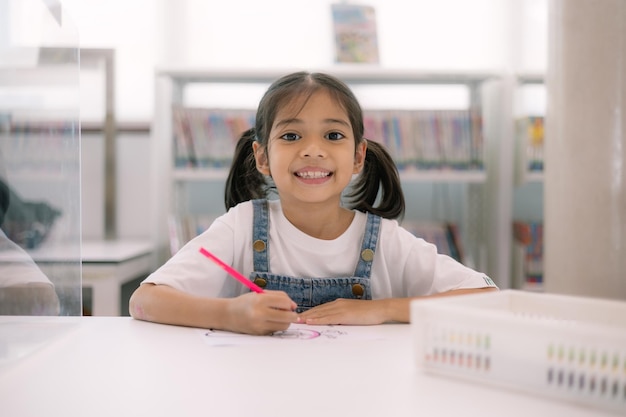 Foto una joven está sentada en un escritorio con un lápiz de colores rojo en la mano