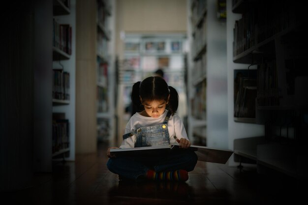 Foto una joven está sentada en el suelo en una biblioteca leyendo un libro