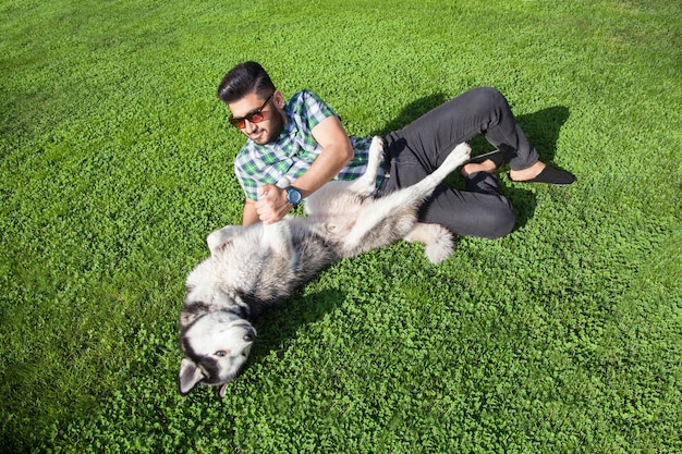 Joven sentado en el césped y disfrutando con su perro