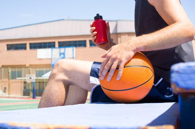 Foto joven sentado en las gradas del campo de baloncesto