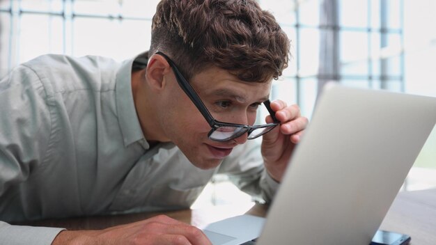 Un joven sentado en la oficina trabajando en una computadora portátil.