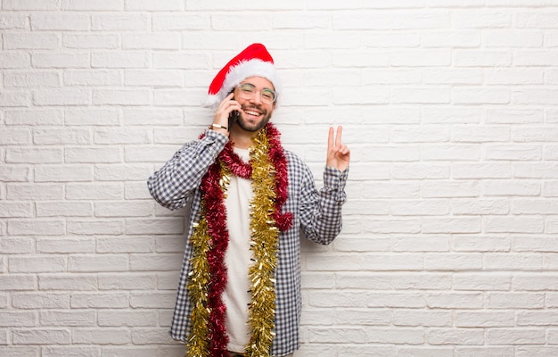 Joven sentado con regalos celebrando la navidad haciendo un gesto de victoria