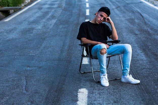 Foto joven sentado en una silla en la carretera