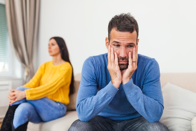 Un joven sentado en un sofá está teniendo una discusión con su novia que tiene la cabeza girada la pareja sentada en el sofá no hablando después de una pelea en casa en la sala de estar